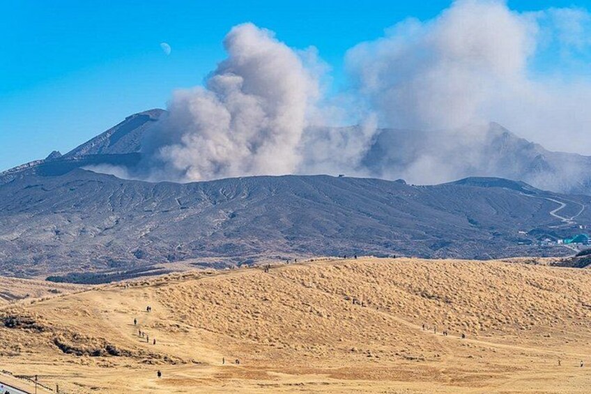 Un paysage volcanique dominé par une montagne imposante, un ciel dégagé et une lune lointaine. 2