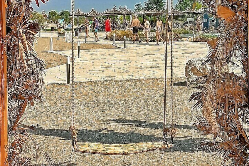 Un parc public avec des balançoires, des palmiers et des gens qui se promènent. 1