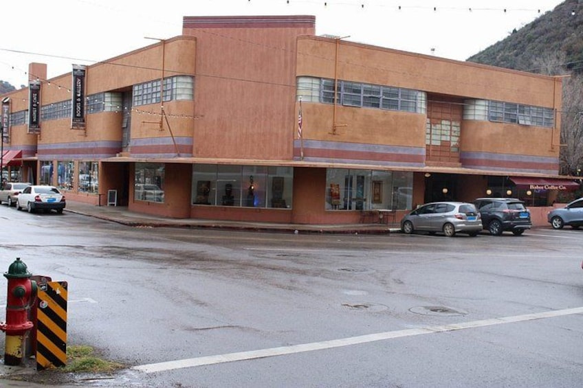 A two-story building with a flat roof and large windows. There are cars parked in front and a fire hydrant on the sidewalk. 2