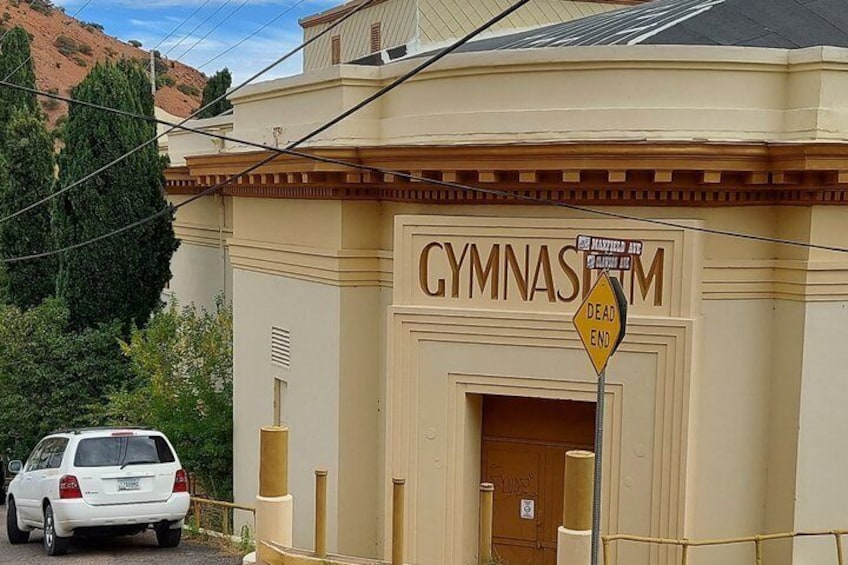 A building with a sign reading 'GYMNASIUM' and a 'DEAD END' sign. 4