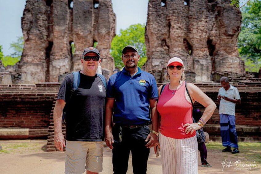 Three people standing in front of ancient stone structures. 1