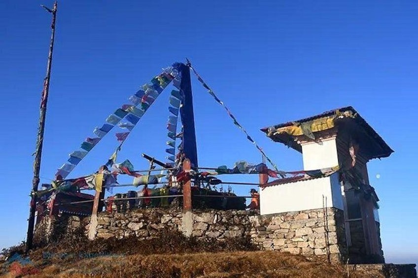 A stone structure with a small building on top, surrounded by colorful prayer flags. 5