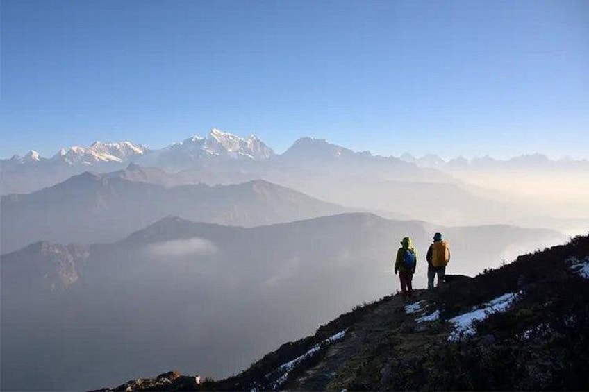 Two hikers on a mountain ridge with snow-capped peaks in the background. 3