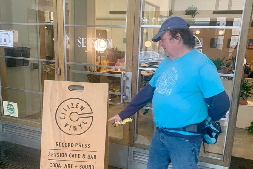 A man standing in front of a glass door with a sign that reads 'SESSION CAFE & BAR' and 'CITIZEN KINT'. 4