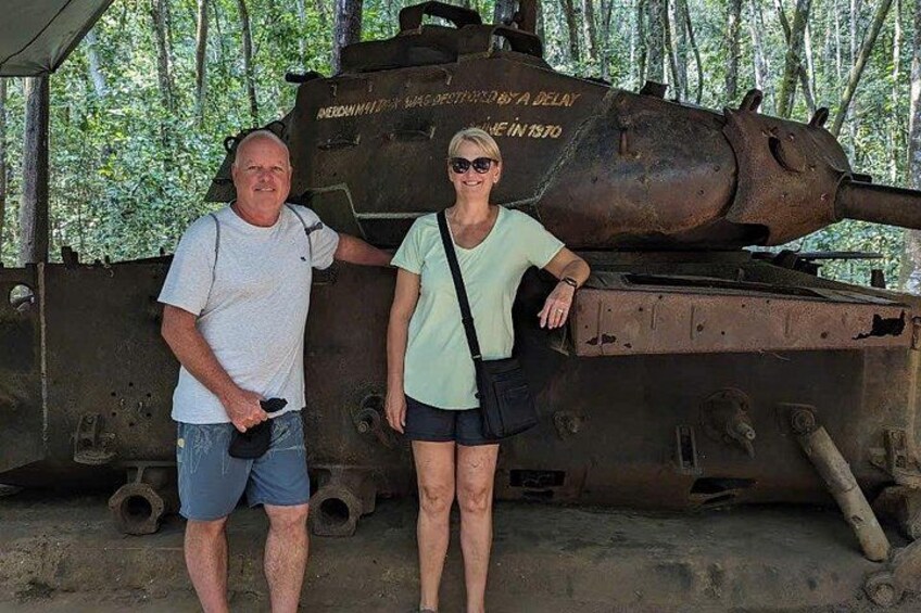 Deux personnes se tiennent devant un grand char d’assaut militaire rouillé, sur lequel on peut voir des inscriptions sur le côté. 4