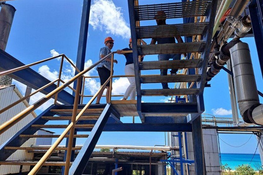 Een bouwplaats met werkende mensen op een metalen trap, industriële gebouwen en een heldere blauwe lucht. 4