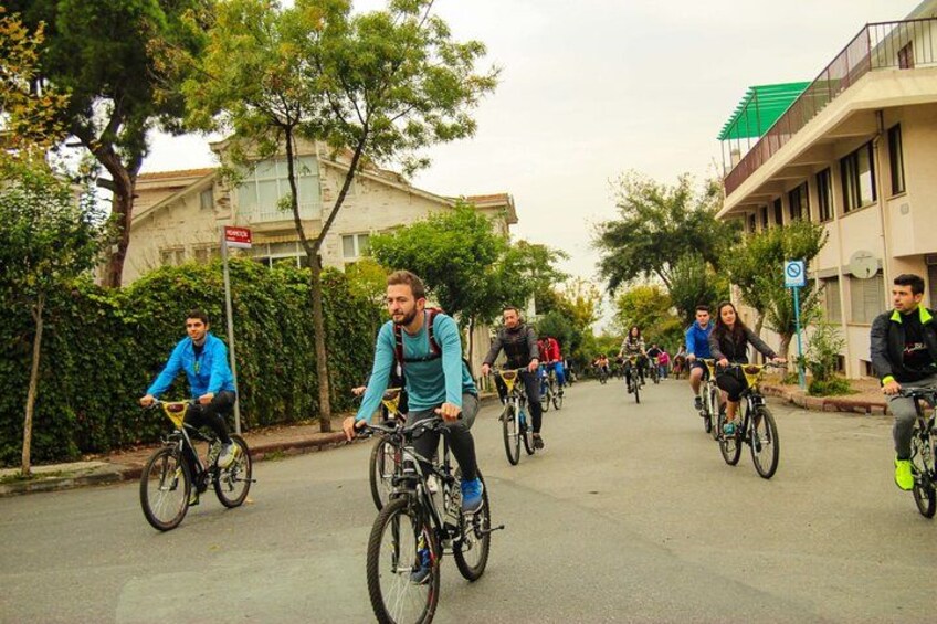 Cyclists riding on a street with buildings and trees in the background. 2