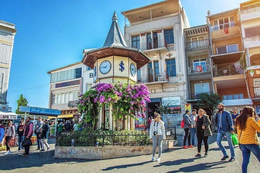 Une place publique avec un beffroi, entourée de bâtiments et de passants. 2