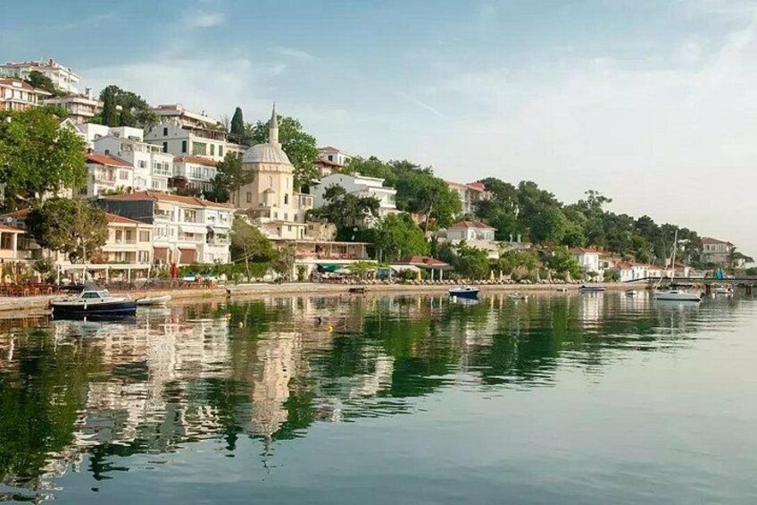 Un paysage paisible au bord de l’eau, avec des bâtiments, une imposante structure en forme de dôme et des bateaux. 3