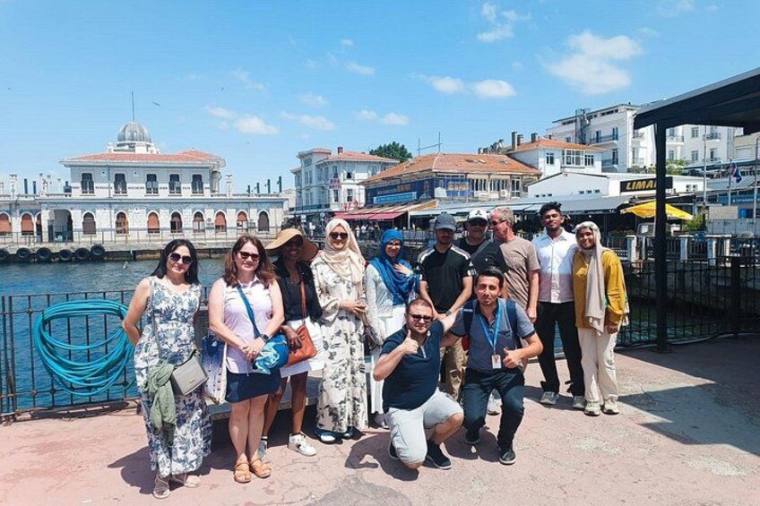 A group of people posing by a waterfront with buildings and a clear sky in the background. 2