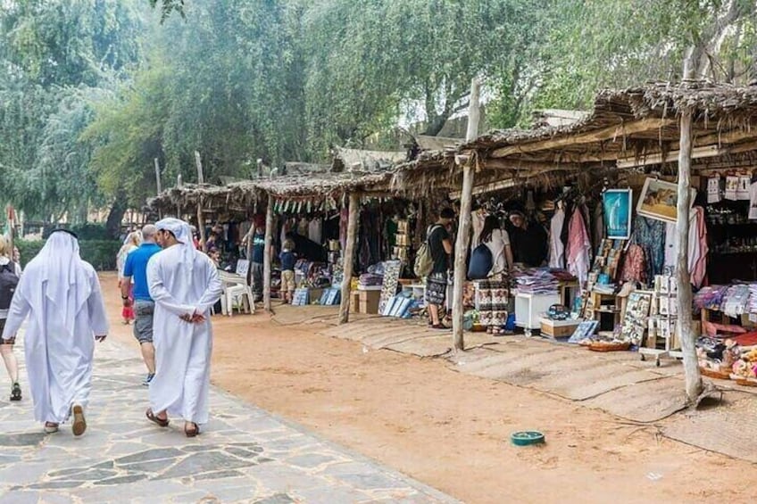 A market with stalls selling textiles and clothing, surrounded by trees. 2