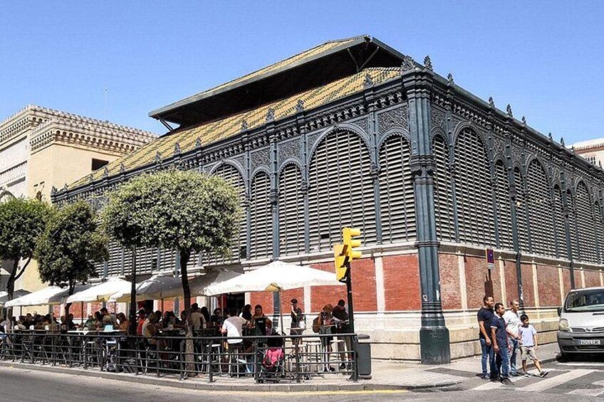 En historisk bygning med detaljeret arkitektur, en gade med mennesker og en parkeret bil. 4