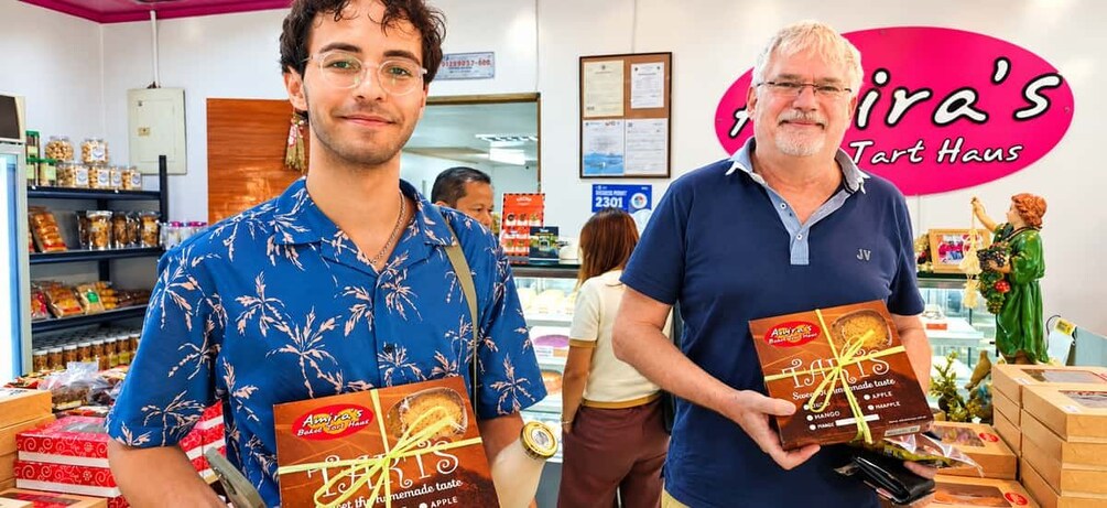 Two people in a bakery holding boxes of baked goods. 5