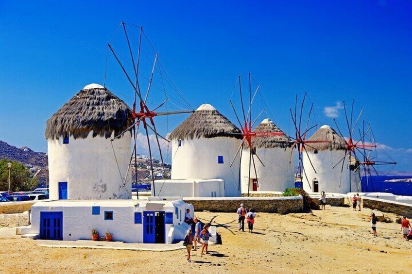 Windmills on a beach with white buildings and blue doors. 1