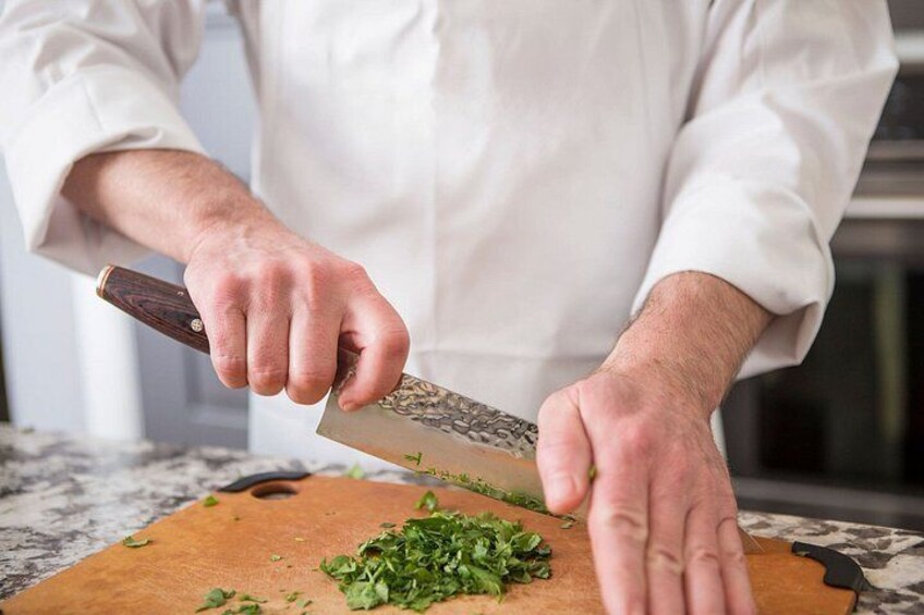 A person chopping herbs on a cutting board. 5