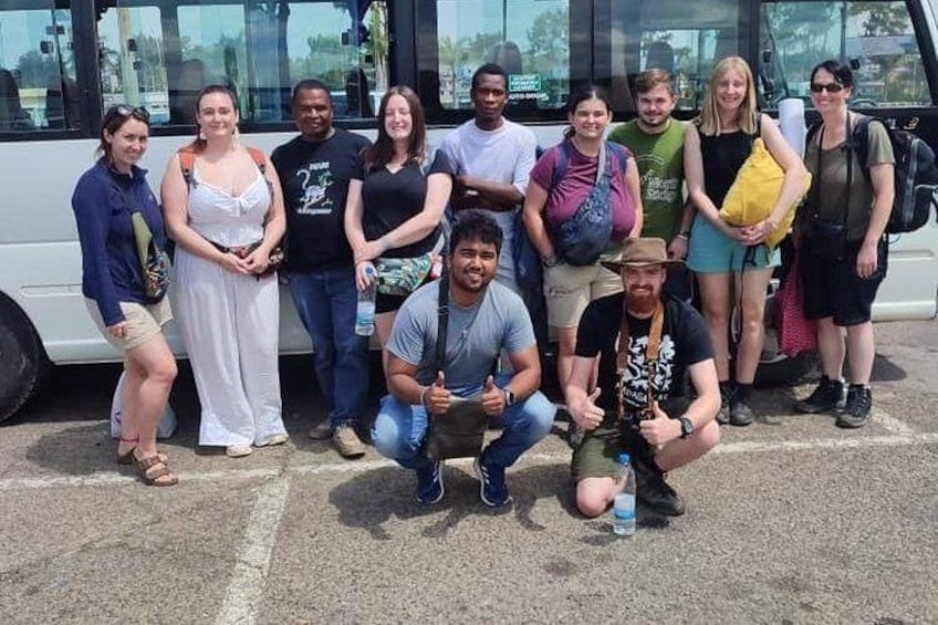 A group of people posing in front of a white bus. 2