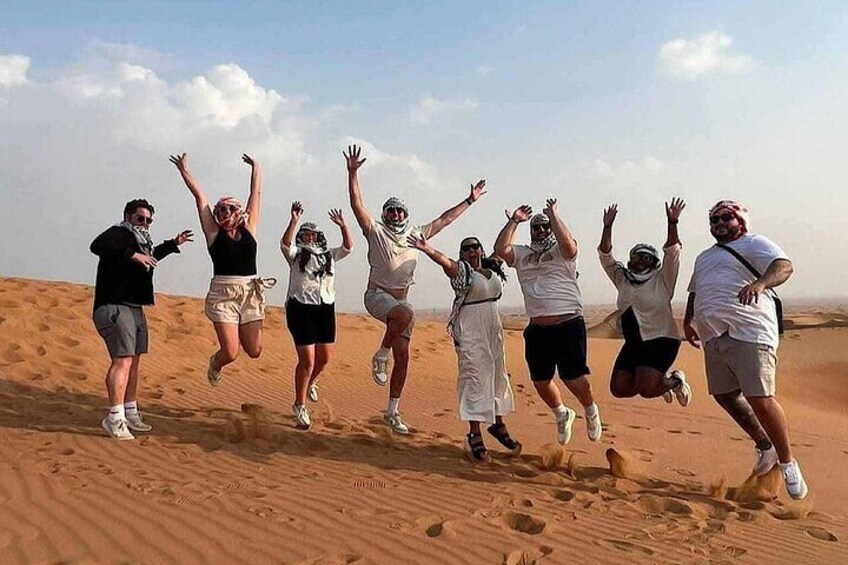 A group of people jumping in a desert with sand dunes in the background. 2