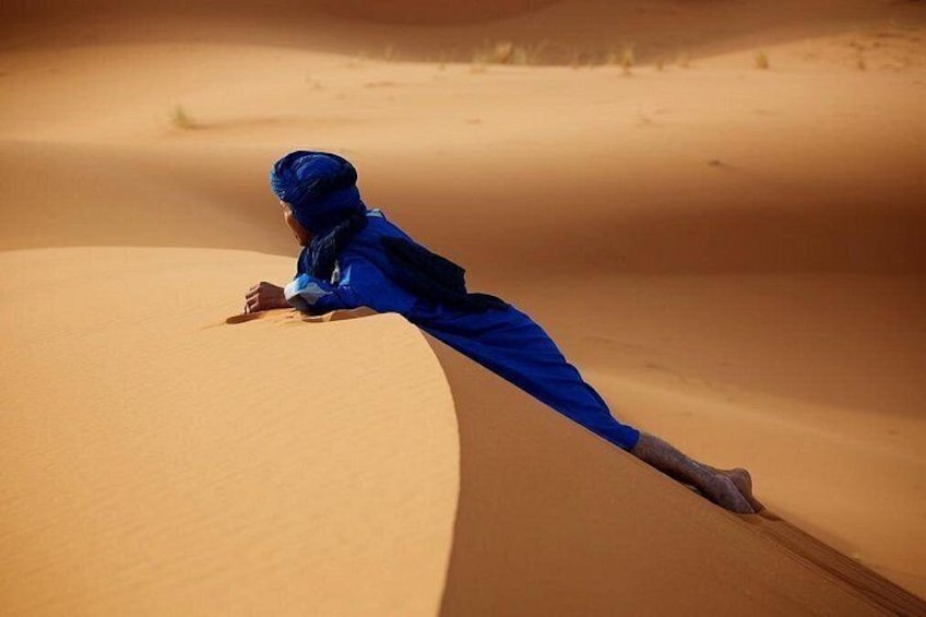 A person in blue attire climbing a sand dune. 2