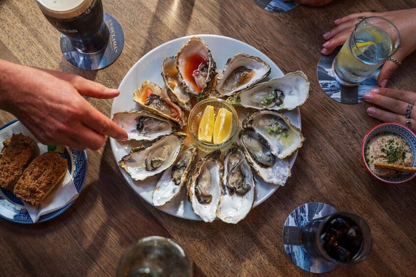 Une assiette d’huîtres, accompagnée de quartiers de citron et d’un verre de vin. 3