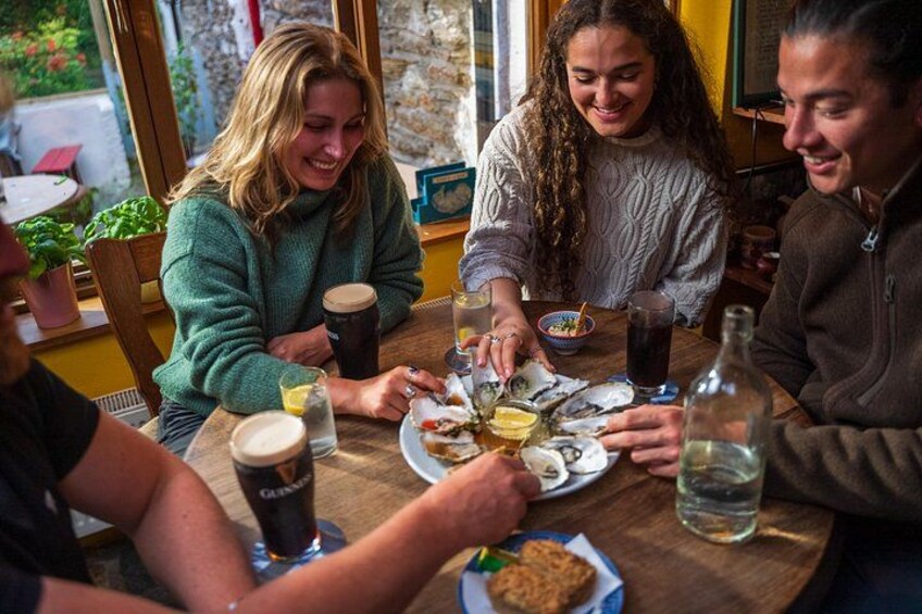 Un groupe de personnes est assis autour d’une table en bois, devant des plats et des boissons. 4