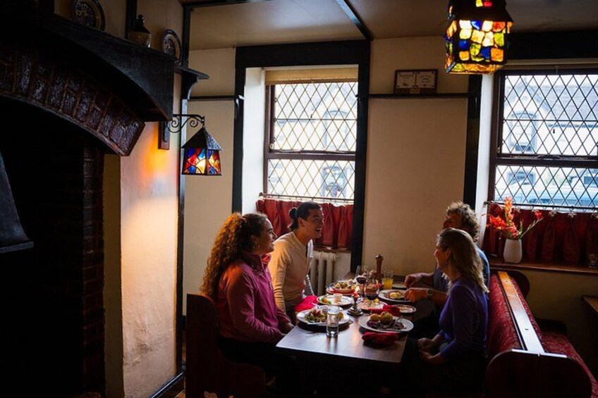 Un groupe de personnes est assis à une table dans un restaurant, qui est décoré de vitraux et possède une cheminée en briques. 2