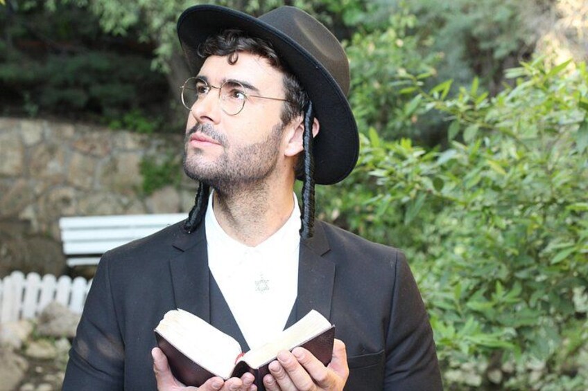 Une personne vêtue d’un costume noir et d’un chapeau, tenant un livre ouvert. 5