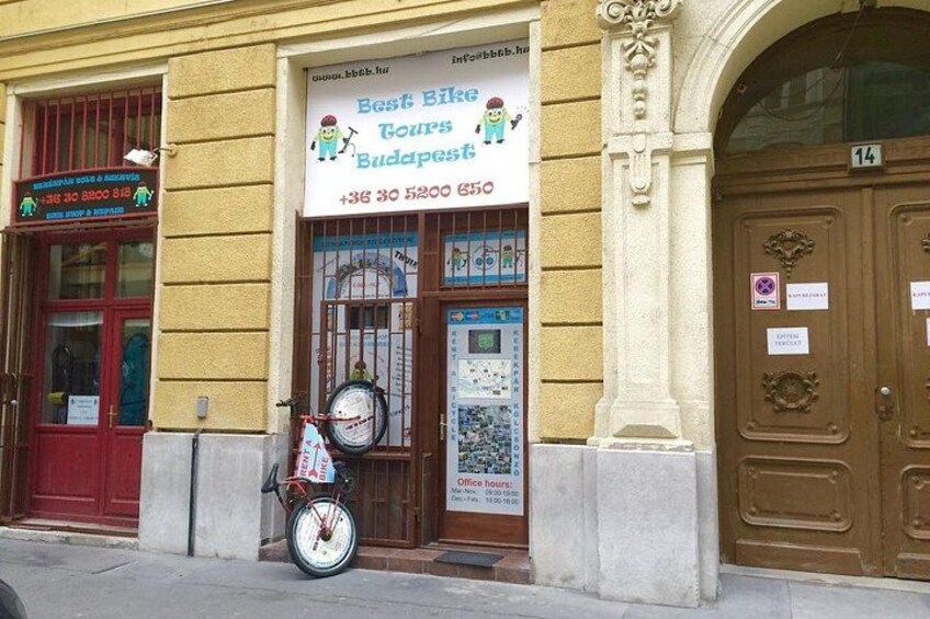 Un bâtiment avec une enseigne indiquant « Meilleures visites guidées à vélo de Budapest » et un vélo garé à l’extérieur. 2