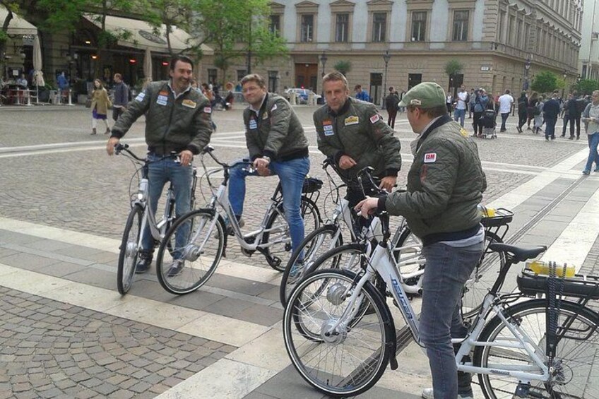 Un groupe de personnes se tient debout autour de vélos dans une rue de la ville. 4