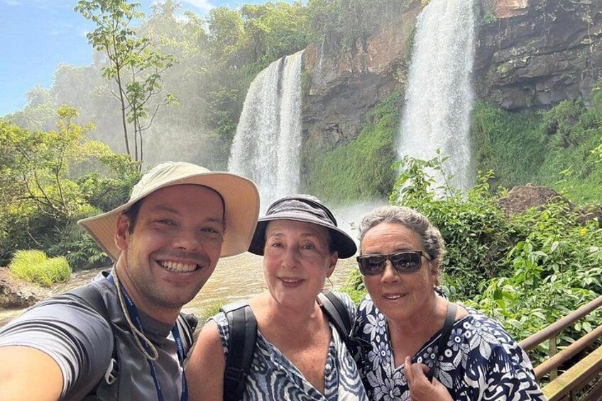 Tres personas tomándose un selfie frente a una cascada y follaje al fondo. 4