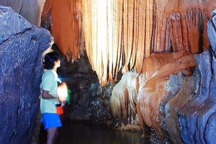 A person exploring a cave with stalactites and stalagmites. 1