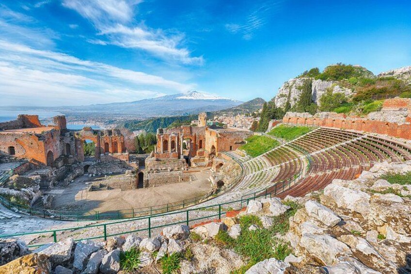 Ancient ruins with a partially intact amphitheater and a mountainous backdrop. 2