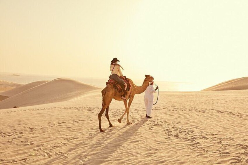 A person riding a camel in a desert with sand dunes in the background. 2