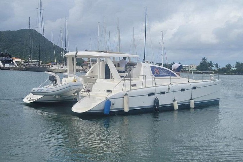 Two white motorboats docked at a marina with a mountainous backdrop. 1