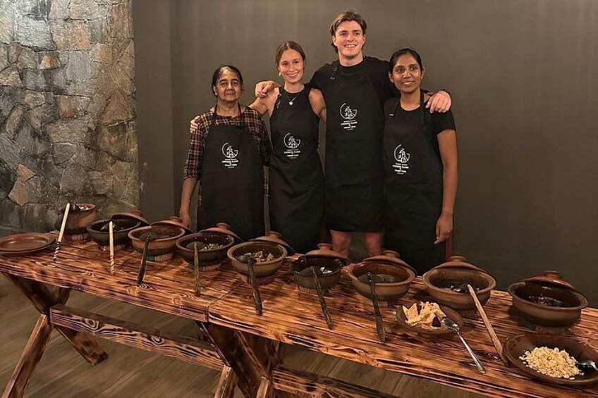 Vier personen staan voor een tafel met kookgerei en kommen. 2