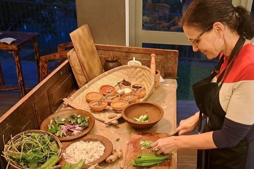 Iemand bereidt eten met diverse ingrediënten en keukengerei op een houten tafel. 5