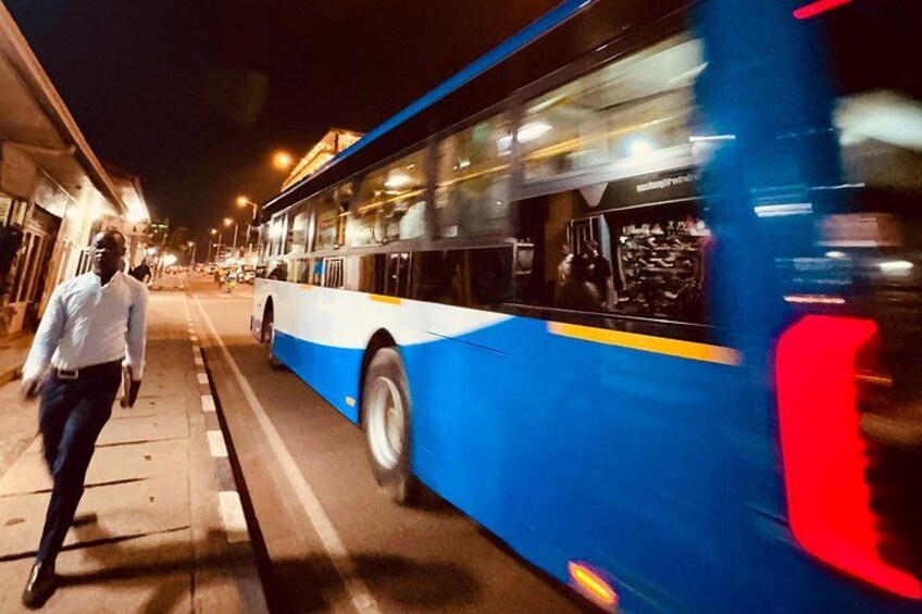 Een blauwe en witte bus op een stadstraat 's nachts. 5