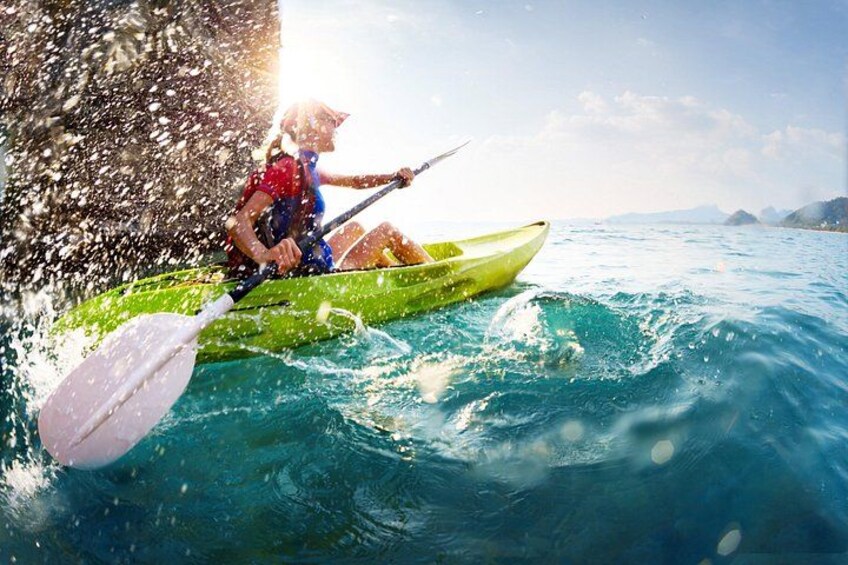 A person kayaking on a body of water with waves, a clear sky, and distant mountains. 3