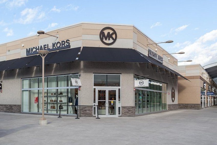 Ein Michael Kors Geschäft mit einer modernen Fassade, großen Glasfenstern und einem gut sichtbaren MK-Logo. 2