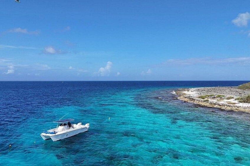 A boat on turquoise waters near a rocky shore. 3