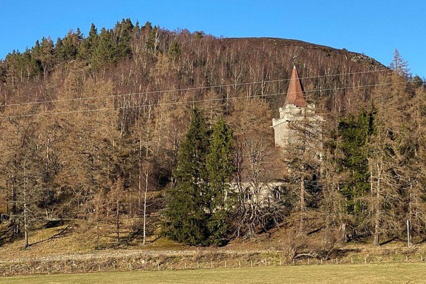 Una colina con una estructura de piedra y una torre de tejado rojo. 3