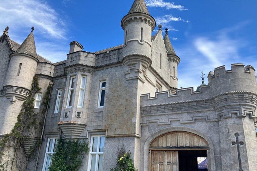 Un castillo con múltiples torres, ventanas de arco y una gran puerta de madera. 2