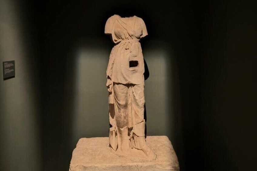 A classical statue on a pedestal in a dimly lit museum. 4