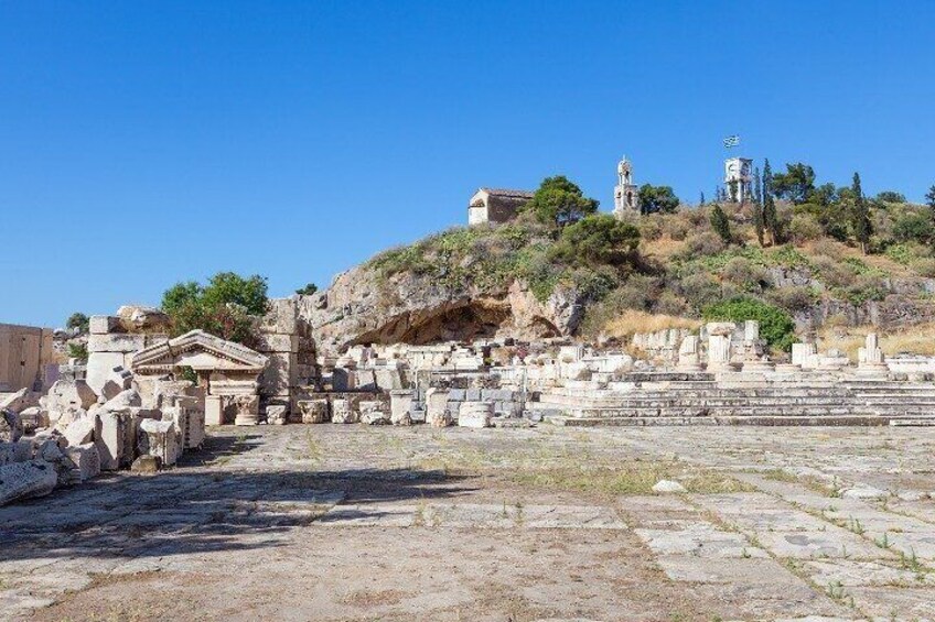 Ancient ruins with columns and steps, a hilltop church, and a clear blue sky. 2