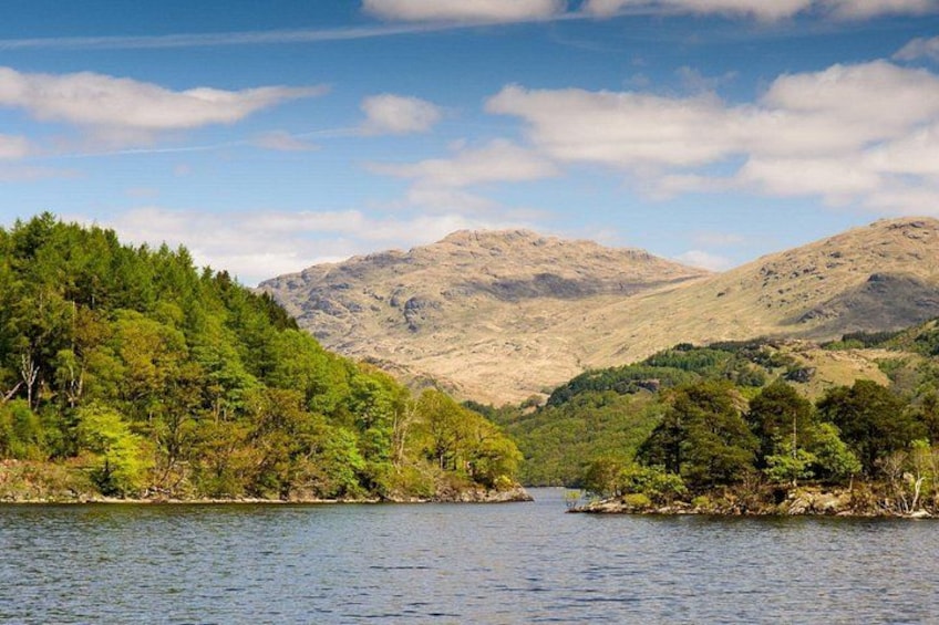 A lake surrounded by hills with dense green forests. 1