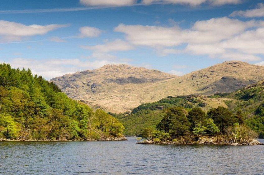 A lake surrounded by hills with dense green forests and a clear sky. 2