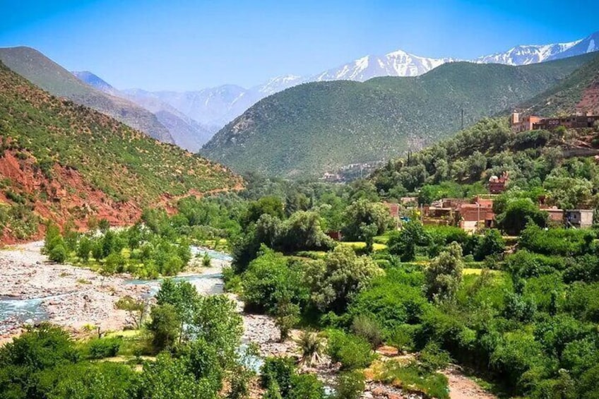A mountainous landscape with a river, greenery, and buildings. 2