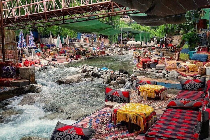 A riverside market with colorful textiles and traditional seating. 4