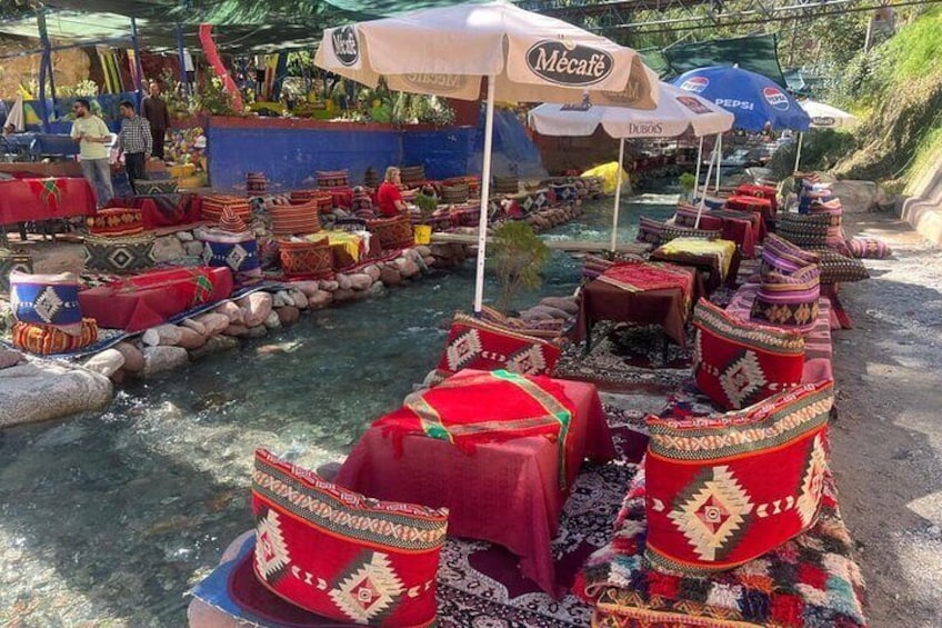 A riverside dining area with canopies and tables set up along the water. 1