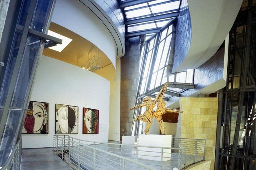 Une galerie d’art contemporain dotée de grandes fenêtres, d’une sculpture et de peintures abstraites. 2