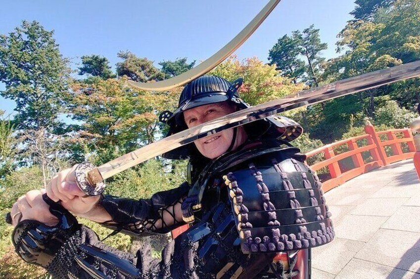 A person in samurai armor holding a sword, standing on a bridge with trees in the background. 4
